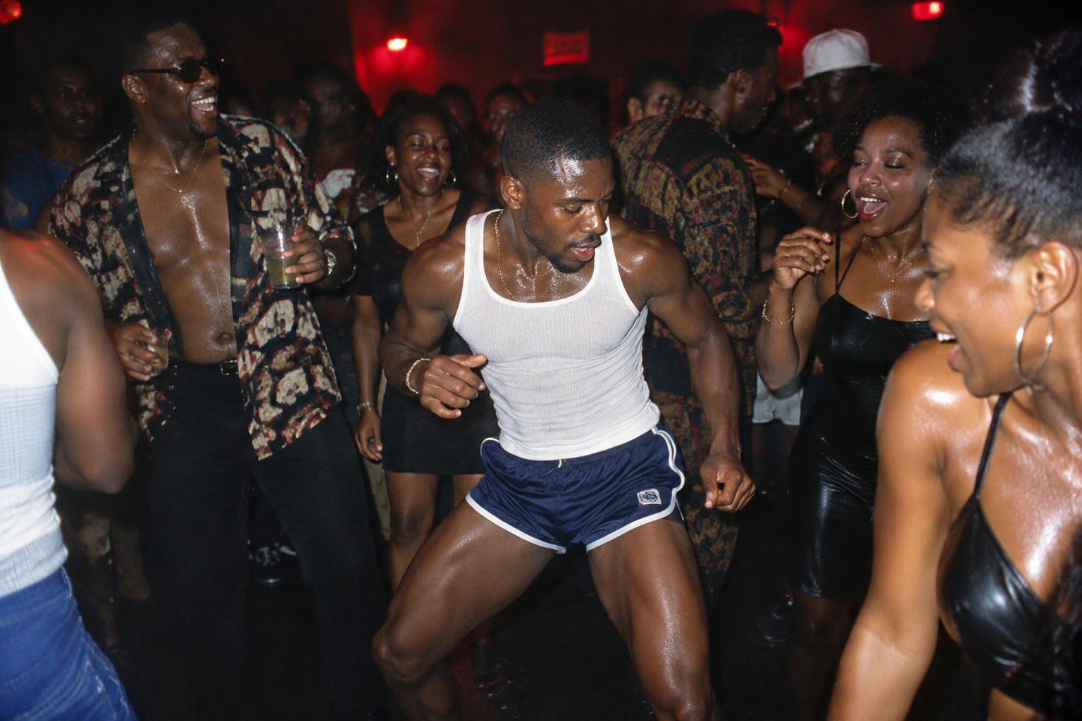 Packed dance floor under red light, flash photography
